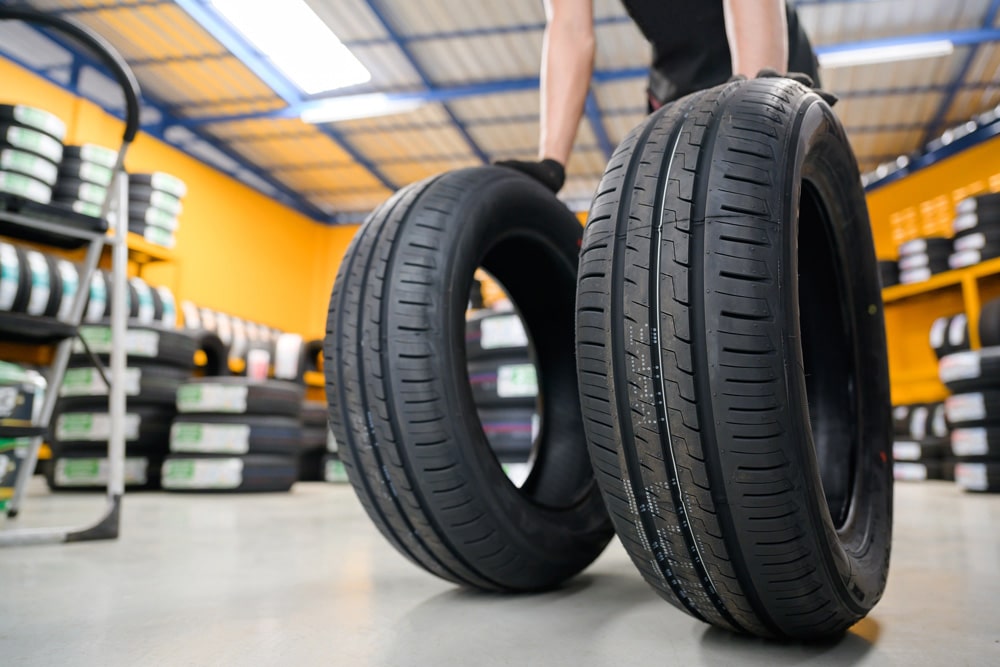 Man Beside Two Tyres In A Tyre Shop